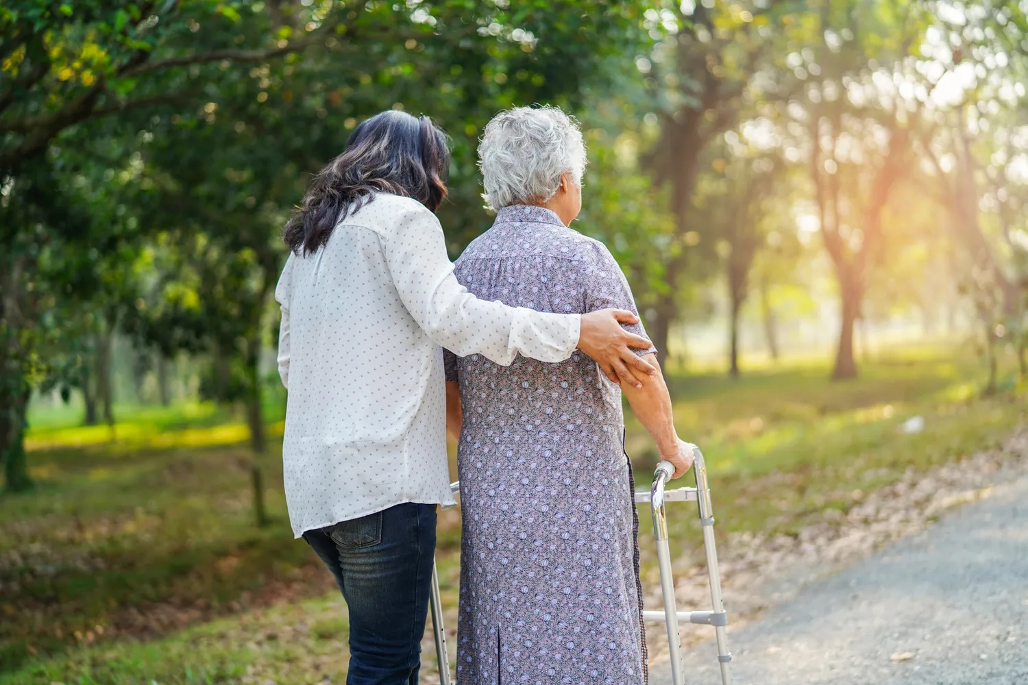 ALLTAGSBEGLEITUNG - Hilfe und Pflege Eine asiatische Seniorin oder ältere Dame benutzt einen Gehhilfe mit guter Gesundheit, während sie in einem fröhlichen, frischen Urlaub im Park spazieren geht.